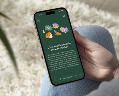Smartphone in einer Hand zeigt die Website familienbund.org mit dem Titel 'Ohne Familien ist kein Staat zu machen' und einem Text zum Familienbund der Katholiken.